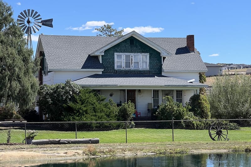 The Lowell ranch house and windmill behind the pond at CALF's Lowell Ranch in Castle Rock, Colorado