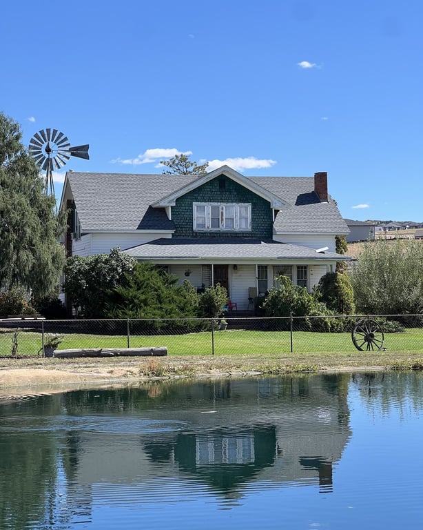 The Lowell ranch house and windmill reflected in the pond at CALF's Lowell Ranch