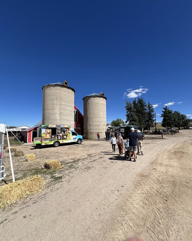 Two concrete silos and a food truck along the dirt road at CALF's Harvest Day