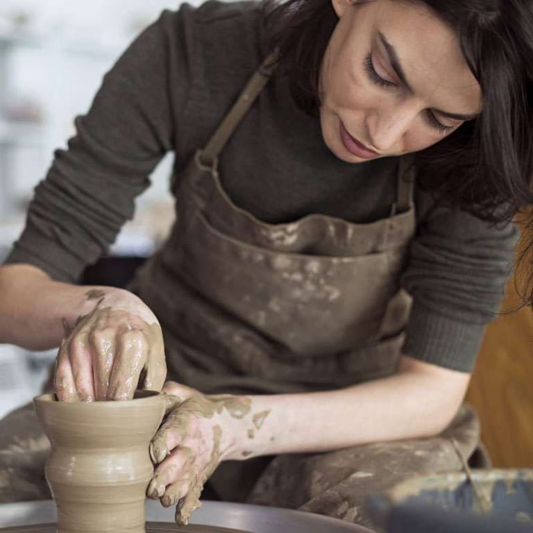Student shaping a vase in a pottery class at the Cantril School Building