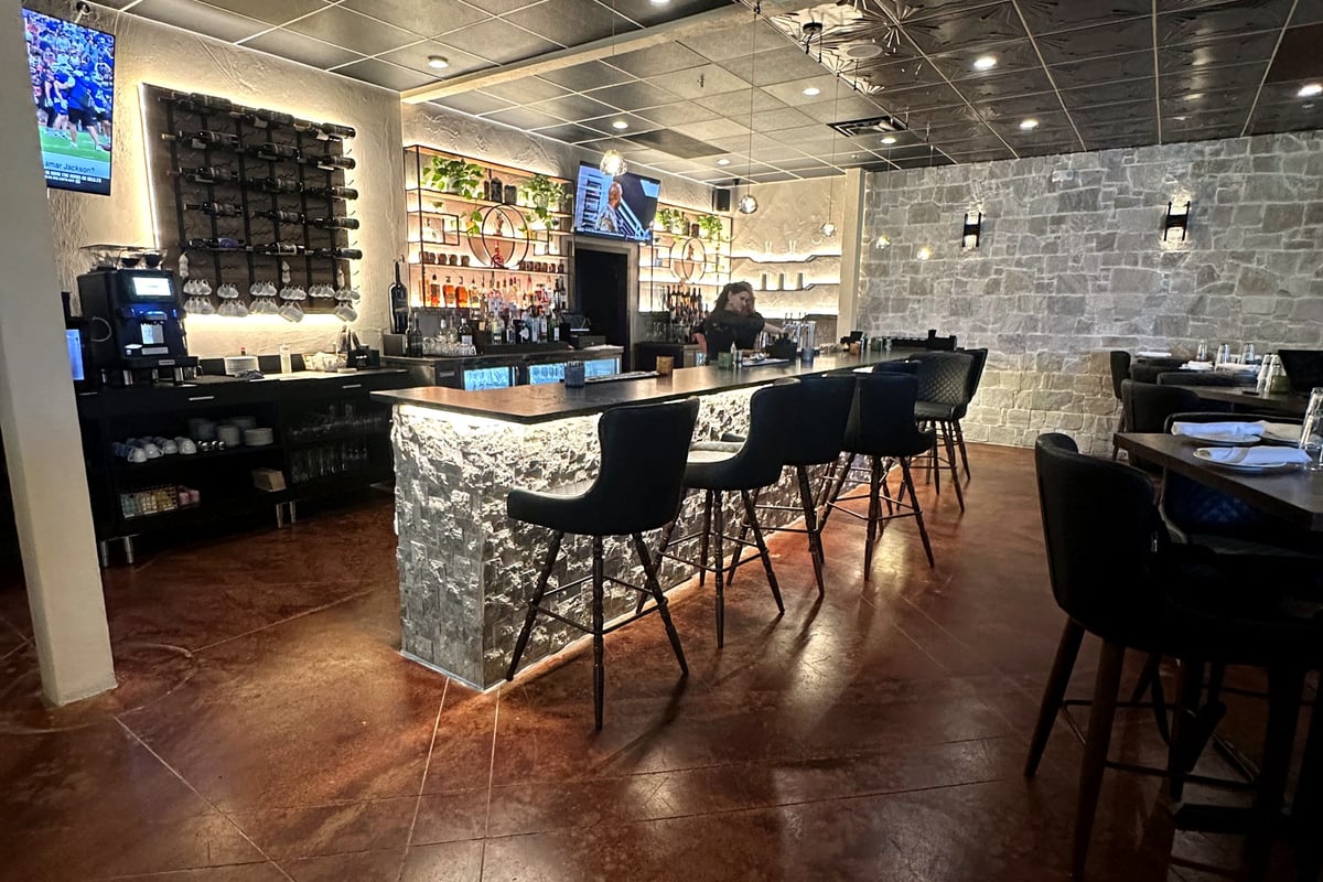 The main dining room at Castello Italiano with wagon-wheel chandeliers and greenery wall