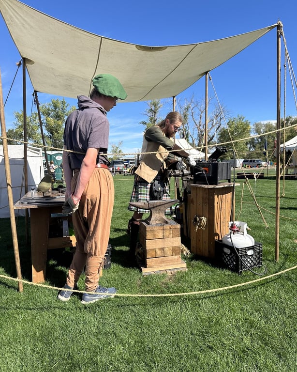 A blacksmith demonstration under a canvas awning at the RenScot tents at the Colorado Highland Games