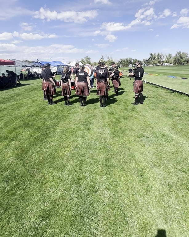 A pipe band in kilts on the field at the Colorado Highland Games