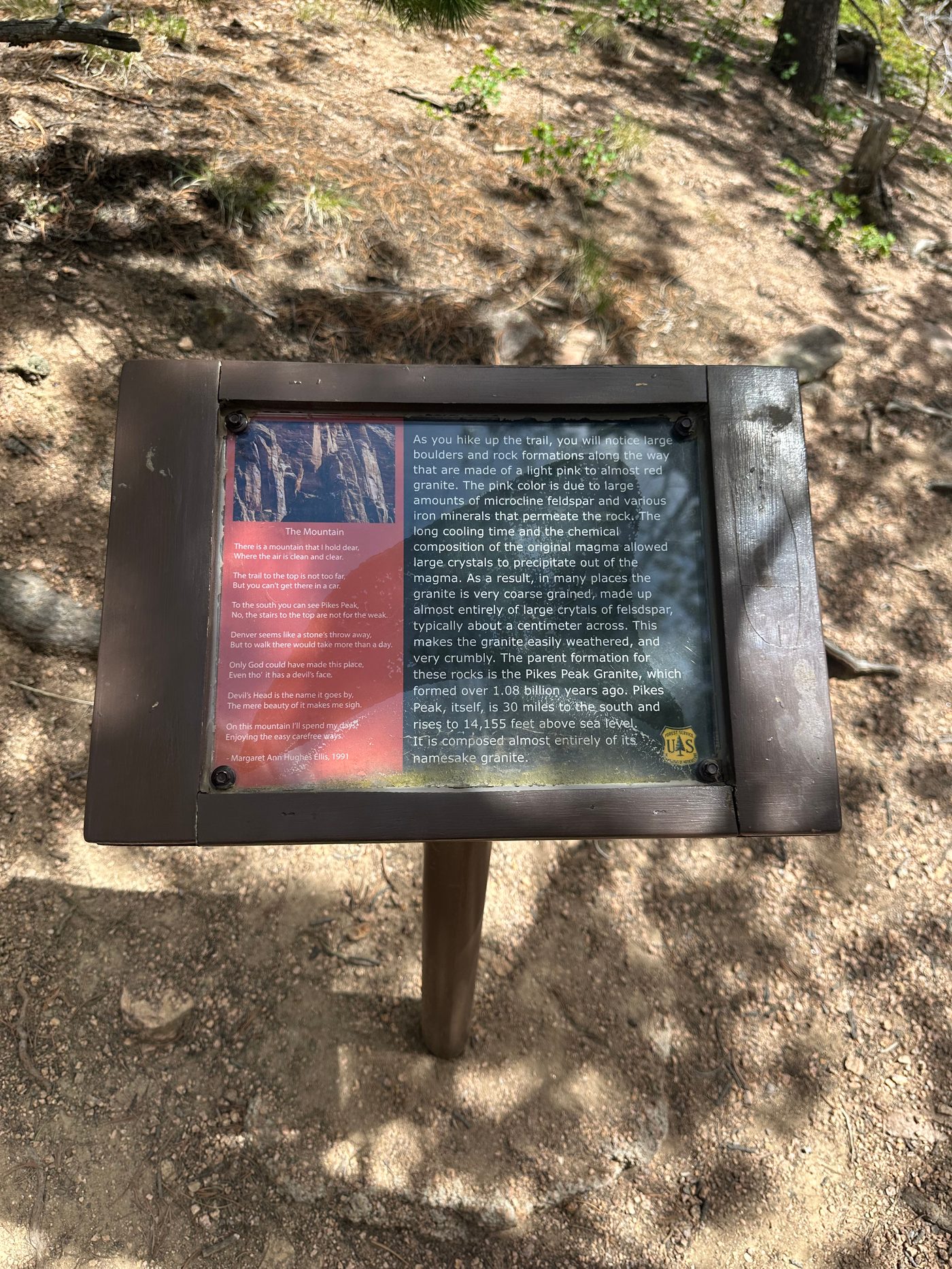 Forest Service interpretive sign on the Devils Head trail carrying the poem The Mountain by Margaret Ann Hughes Ellis and an explanation of the pink Pikes Peak granite