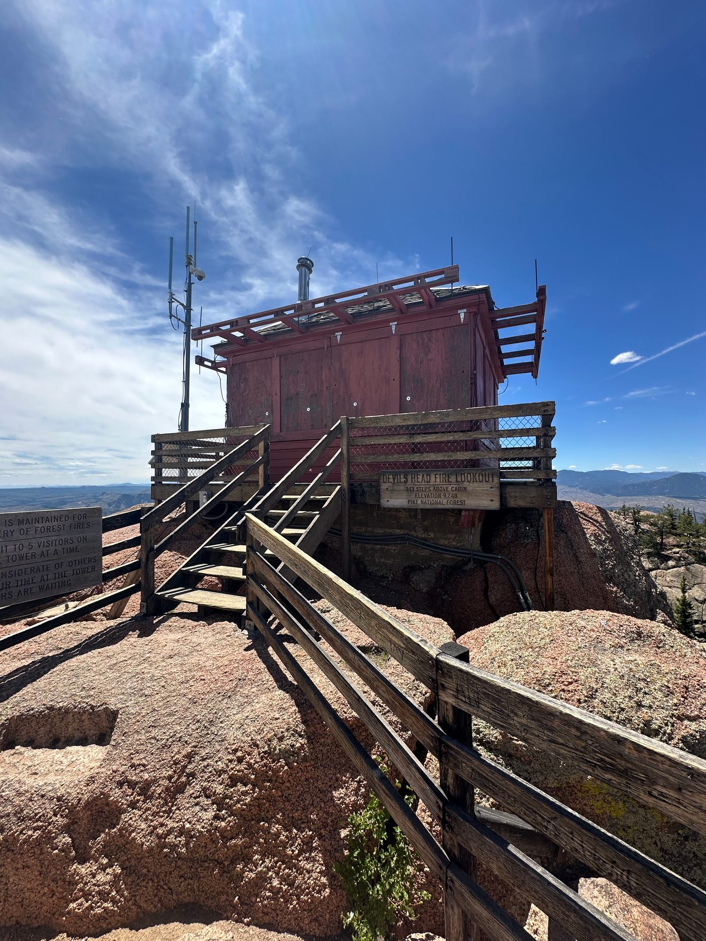 The Devils Head fire lookout at the top of the stairs, with the Forest Service sign reading 143 steps above cabin, elevation 9,748, Pike National Forest