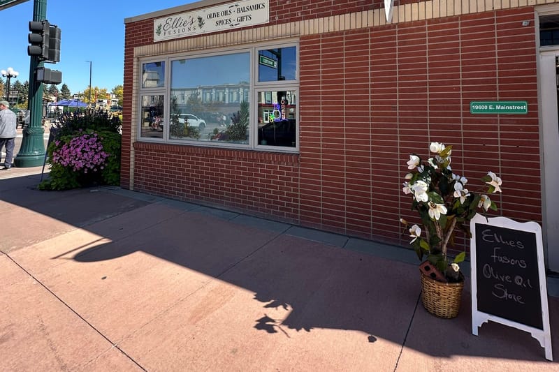 The Ellie's Fusions storefront at 19600 E Mainstreet in downtown Parker, Colorado, with its olive oils, balsamics, spices and gifts sign and address plaque