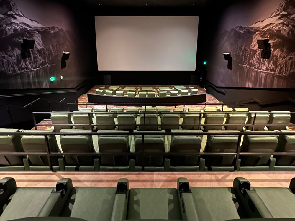 Inside an Emagine Parker auditorium — big screen, heated recliners in tiered rows, and Colorado landscape murals on the walls
