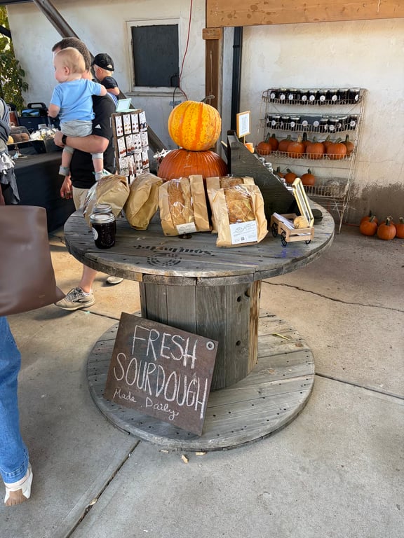 Bags of bread on a cable-spool table under a Fresh Sourdough Made Daily sign at the Gilly's store
