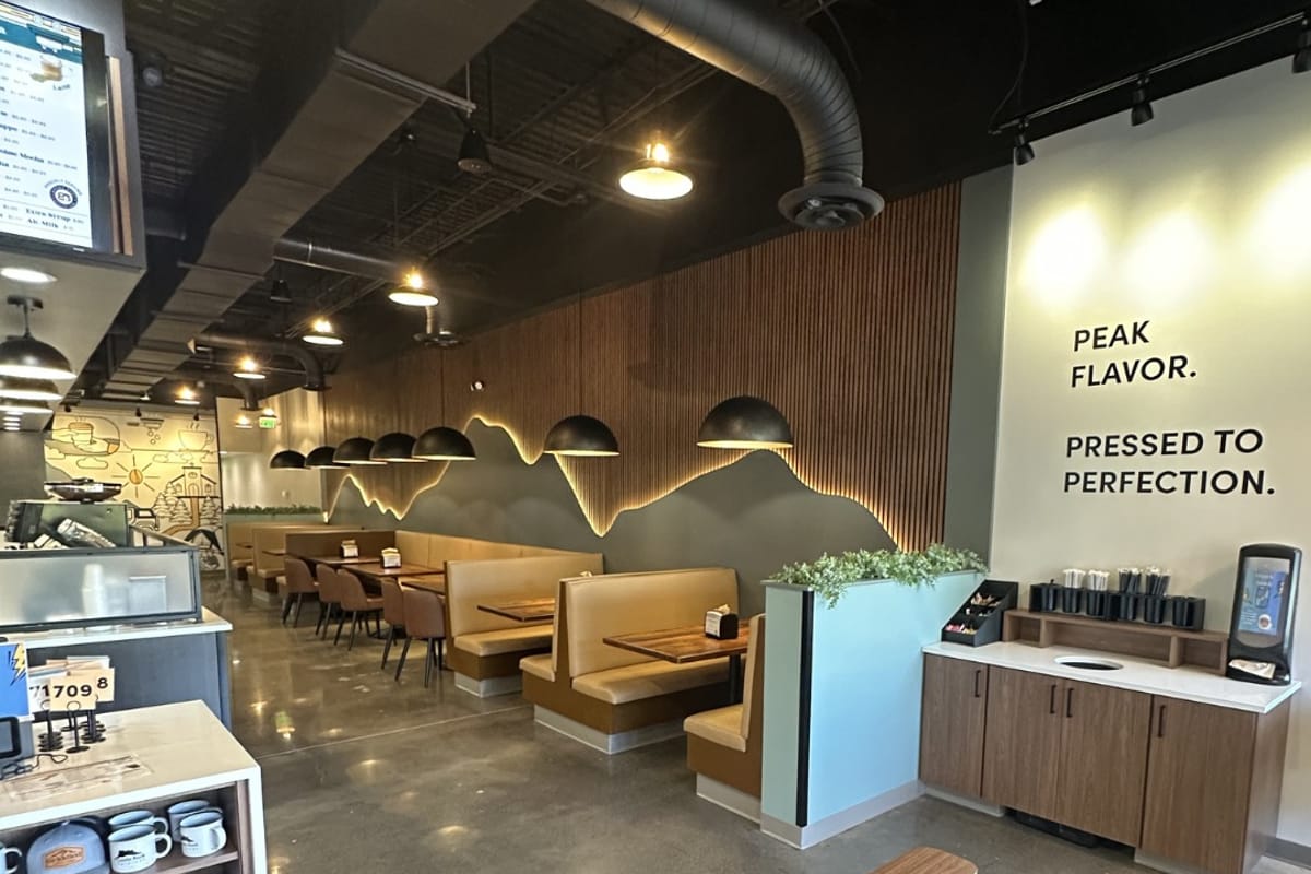 Inside Griddled — booth seating under the mountain-lit wood wall and the Peak Flavor, Pressed to Perfection tagline
