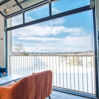 Seating by an open garage door with a view at Happy Crew Coffee House