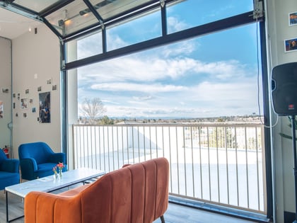 Seating by an open garage door with a view at Happy Crew Coffee House