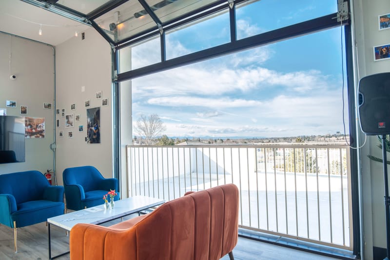 Seating by an open garage door with a view at Happy Crew Coffee House