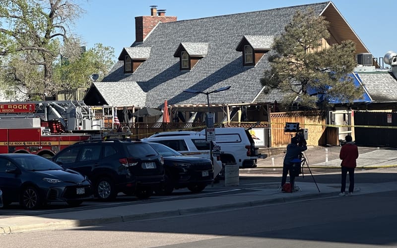 Castle Rock Fire & Rescue ladder truck and investigation SUV outside the Hideaway Bar & Grill on Wednesday morning, May 13, 2026, with yellow scene tape across the front and a news crew set up across the street. Photo by Connor Tien.