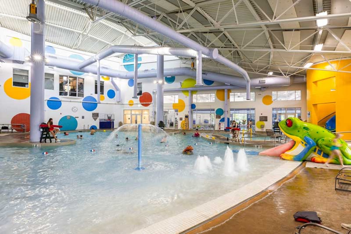 The indoor leisure pool at the Eastridge Rec Center with a frog slide and fountains under a polka-dot wall