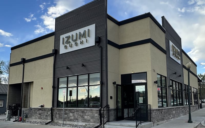 Izumi Sushi storefront with prominent signage on Third Street in downtown Castle Rock at golden hour with dramatic clouds overhead.