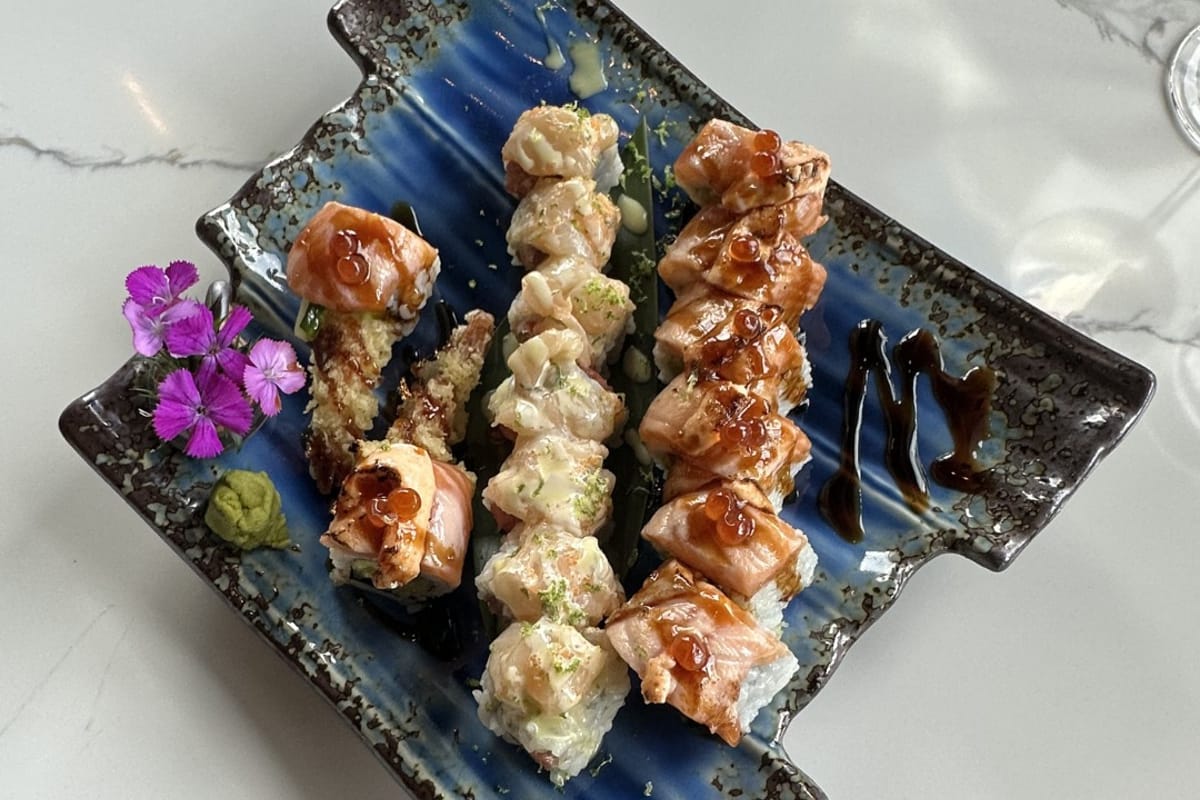 Multi-roll platter on blue triangular ceramic at Izumi Sushi — Izumi Roll center, Toro Uni Rolls flanking