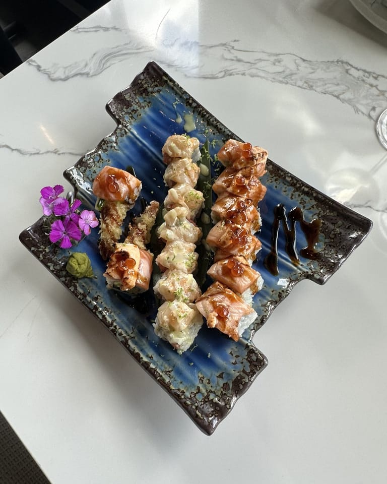 Multi-roll platter on blue triangular ceramic at Izumi Sushi — Izumi Roll center, Toro Uni Rolls flanking