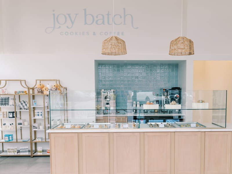 Joy Batch Cookies & Coffee storefront counter in Highlands Ranch, with the shop's logo, pastry case and coffee bar