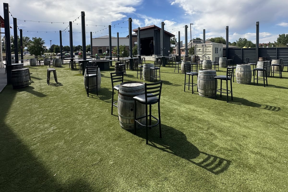 The outdoor turf beer garden with barrel tables at JP Cocina & Cantina