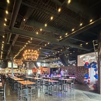 The main dining room at JP Cocina & Cantina in Parker, Colorado, with chandeliers, brick walls and high-top tables