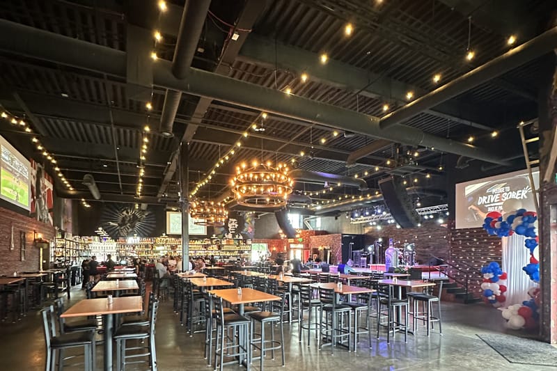 The main dining room at JP Cocina & Cantina in Parker, Colorado, with chandeliers, brick walls and high-top tables
