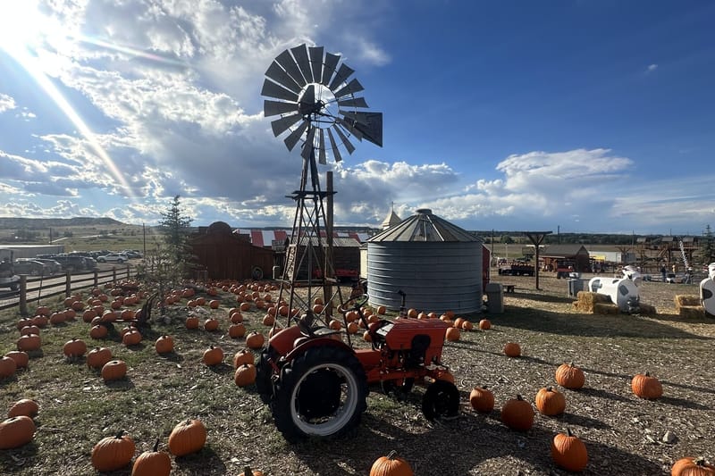 A windmill, an orange tractor and rows of pumpkins under a big Colorado sky at Lone Creek Farms in Franktown