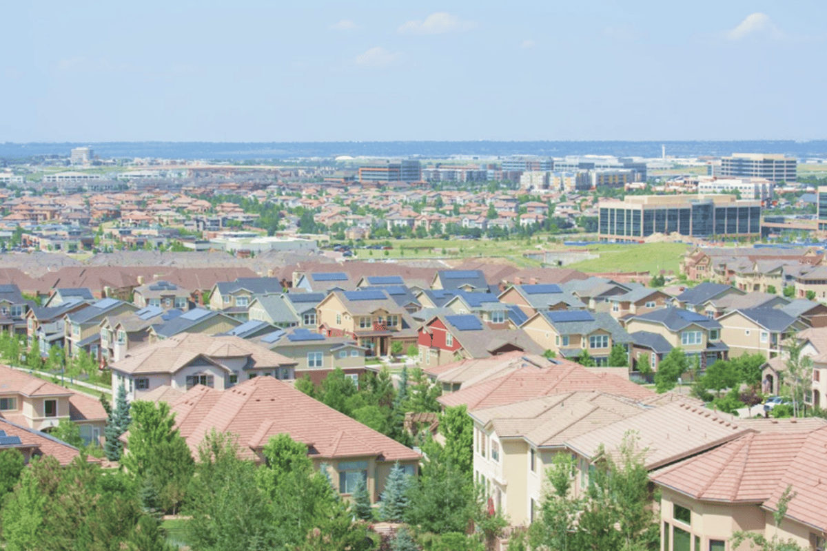 Looking north over Lone Tree rooftops with solar panels toward the office buildings along I-25 and the Denver skyline