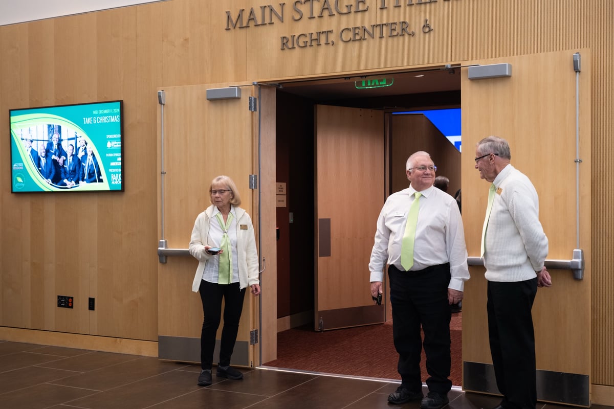 Ushers in white shirts and green ties at the open doors of the Main Stage Theater inside the Lone Tree Arts Center