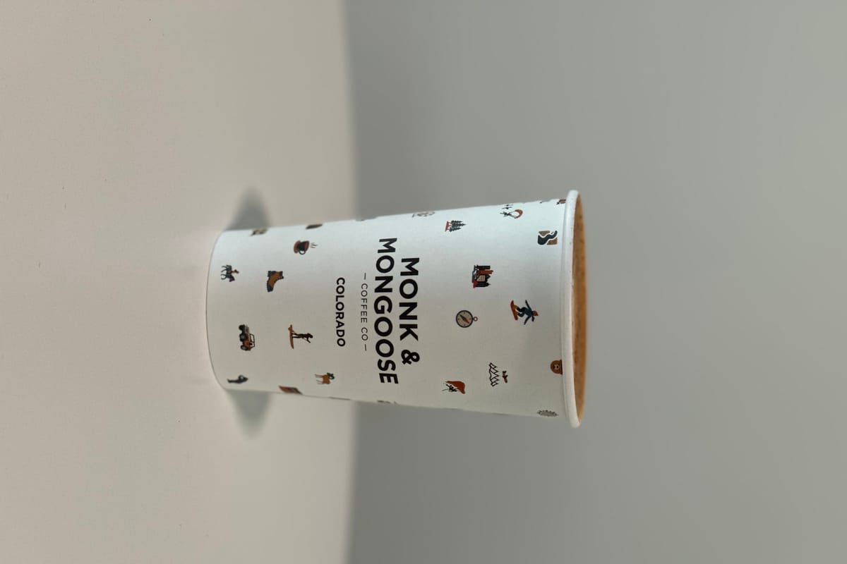 A Monk & Mongoose Coffee Co. Colorado-branded paper cup