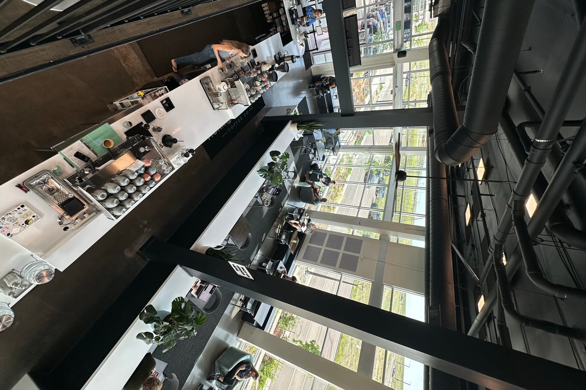 Overhead view of the two-story Monk & Mongoose High Note coffee shop, looking down from the loft over the espresso bar and seating