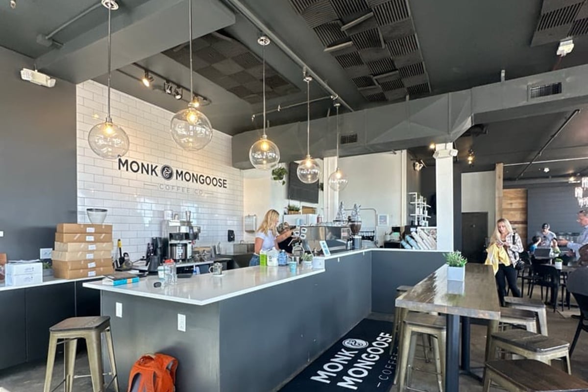 Baristas working behind the tiled counter under the Monk & Mongoose Coffee Co. wall lettering at the RidgeGate location