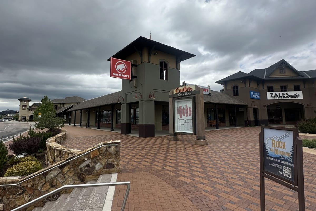 Clock tower at Outlets at Castle Rock with Mammut sign, directory map, and Rock the Mountain summer concert series easel