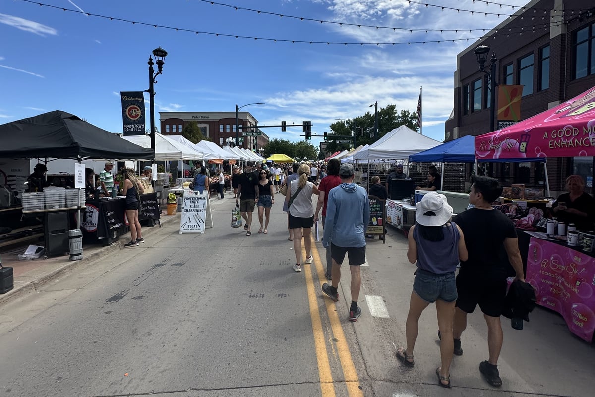 Families walking down the middle of Mainstreet between vendor tents at the Sunday Parker Farmers Market
