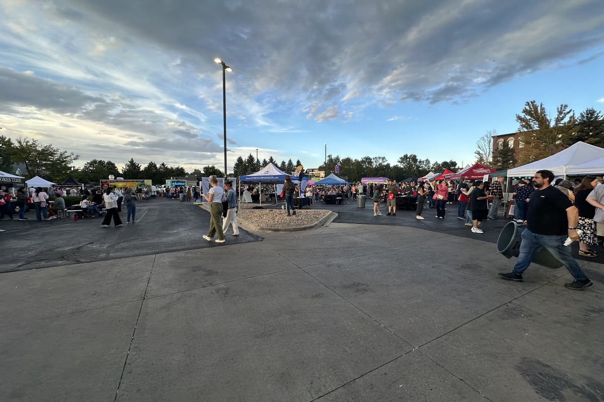 Vendor tents and a crowd in the Parker Station lot at Yelp's Taste of Parker under a streaked evening sky