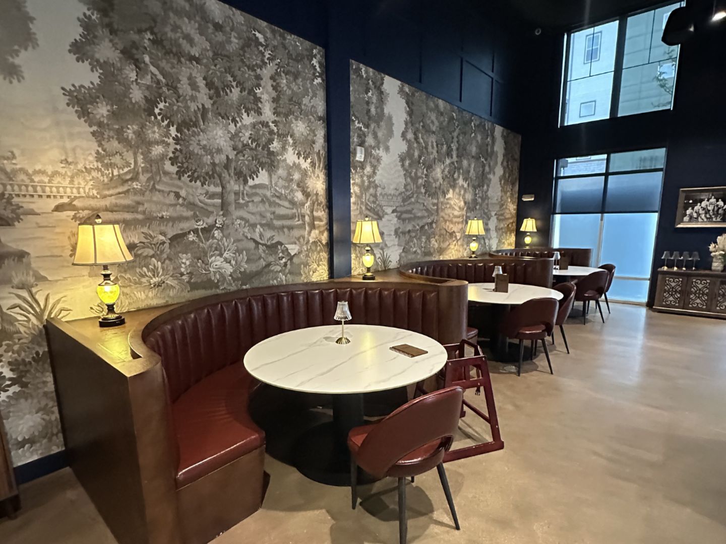 Curved booth against black-and-white landscape wallpaper at Champagne Velvet Proper Kitchen & Bar in Castle Rock