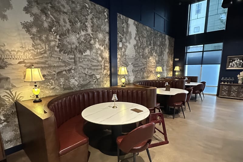 Curved booth against black-and-white landscape wallpaper at Champagne Velvet Proper Kitchen & Bar in Castle Rock