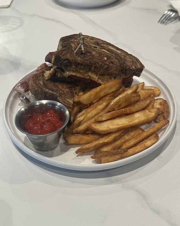 Million Dollar Reuben at Champagne Velvet Proper Kitchen & Bar — thick-cut corned beef, melted swiss, sauerkraut on toasted marble rye, brewery fries