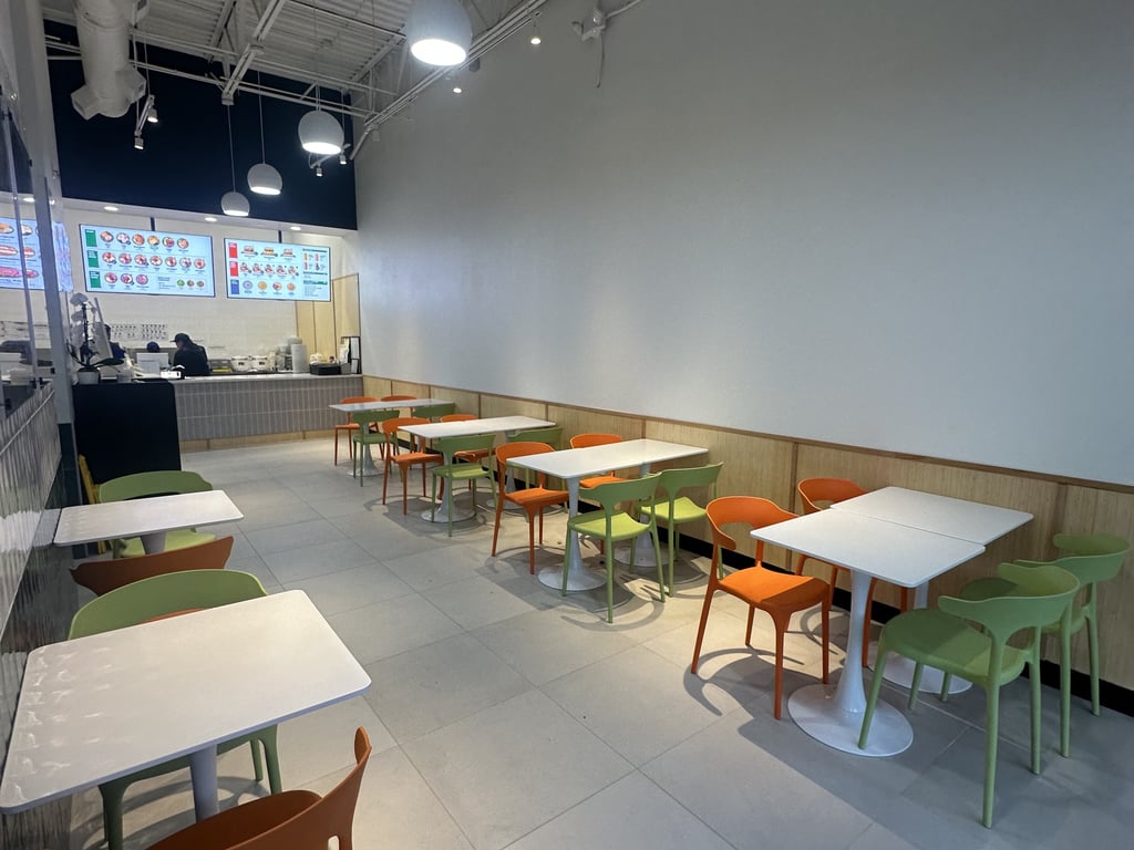 The dining room at Salady Parker, with orange and green seating and the lit menu boards behind the counter