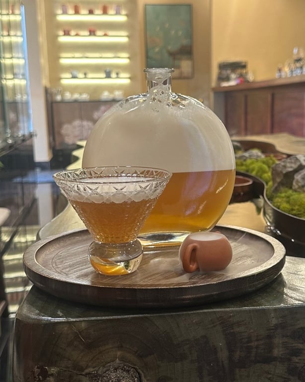 The Cloud Mist Tea in a round glass carafe with a tasting cup on a wood tray at SereniTea