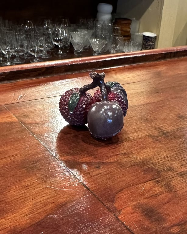 SereniTea's tea pet: three clay berries sitting on the wood tea bar