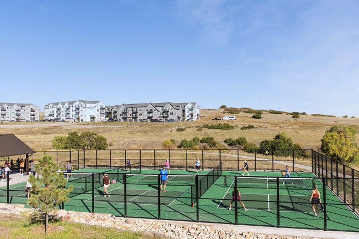 Players on the four fenced pickleball courts at Canyon Village in The Canyons, with new homes on the hill behind