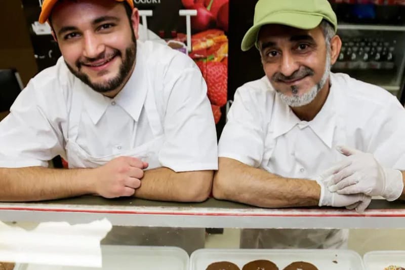 Two bakers behind a case of donuts at The Donut House