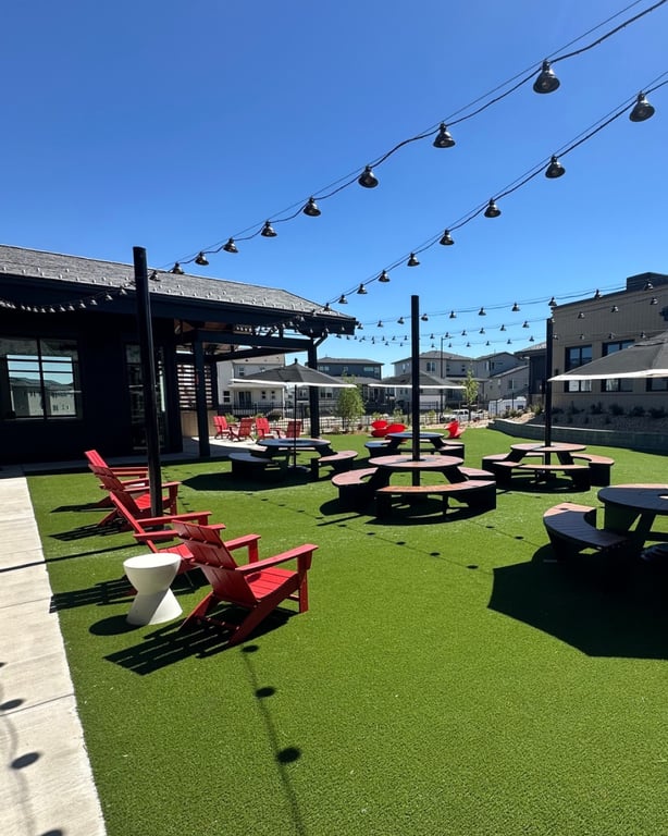 The Groove patio in Lone Tree: red Adirondack chairs and picnic tables on turf under string lights