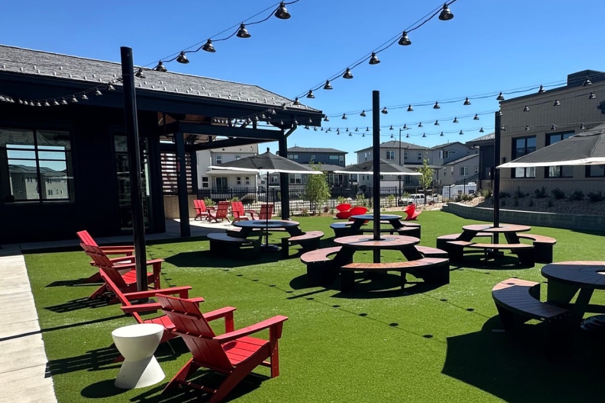 The Groove patio in Lone Tree: red Adirondack chairs and picnic tables on turf under string lights