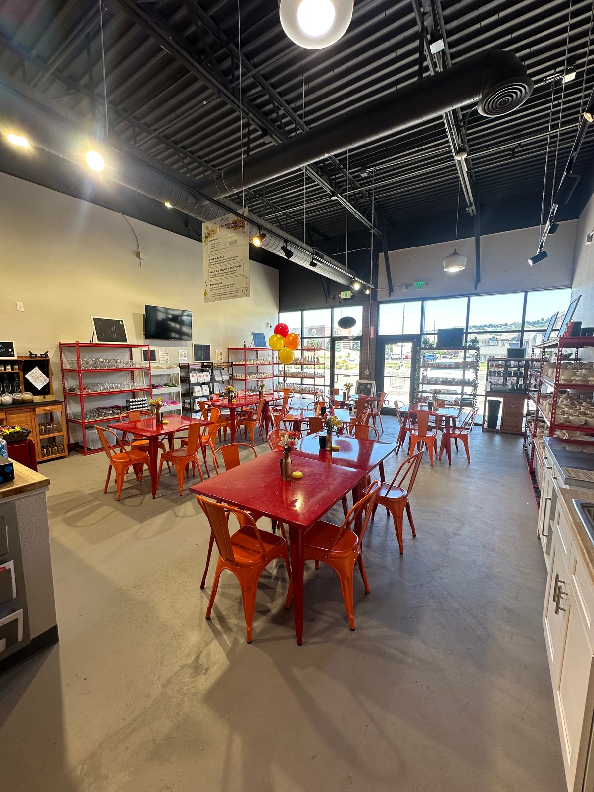 The main studio floor at The Hot Spot Studios in Castle Rock, with worktables and shelves of pieces to paint