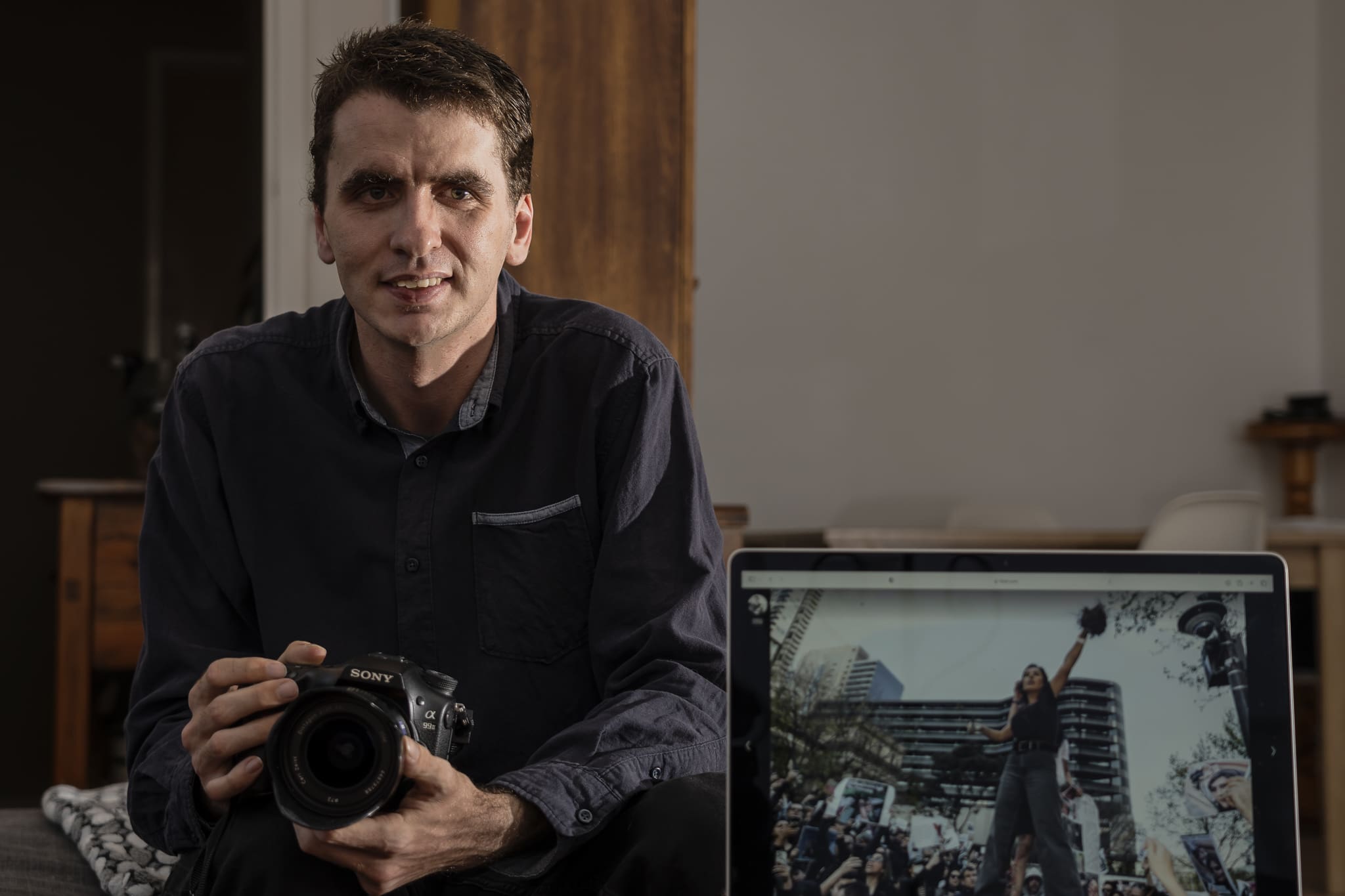 Matt Hrkac posing for a photo with his winning entry (seen on screen on the bottom right)