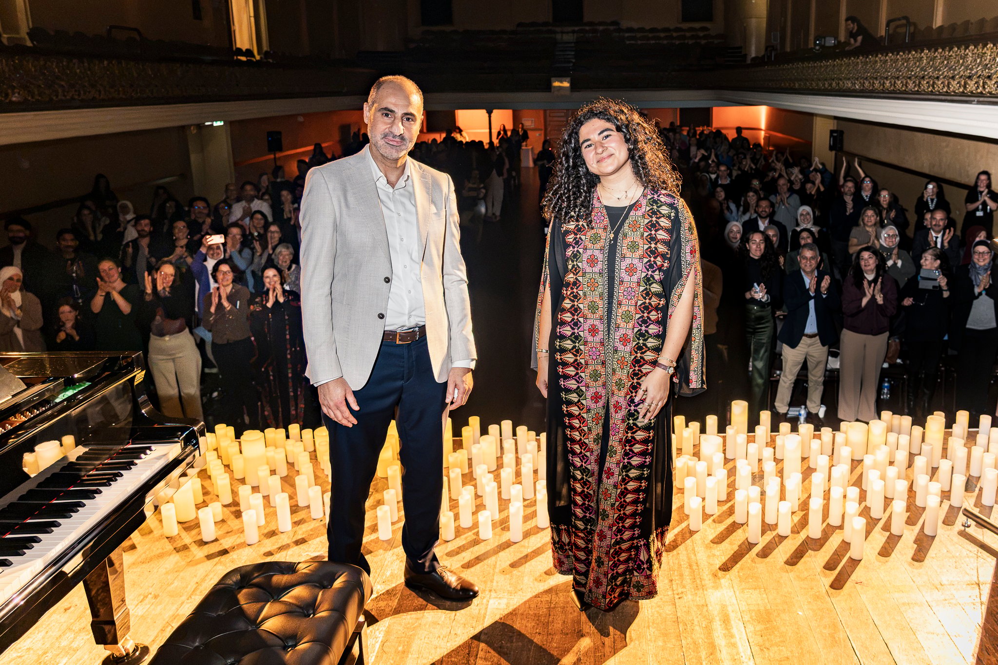 Bahar Skaik stands with Heba Tayeh with the crowd behind then applauding.