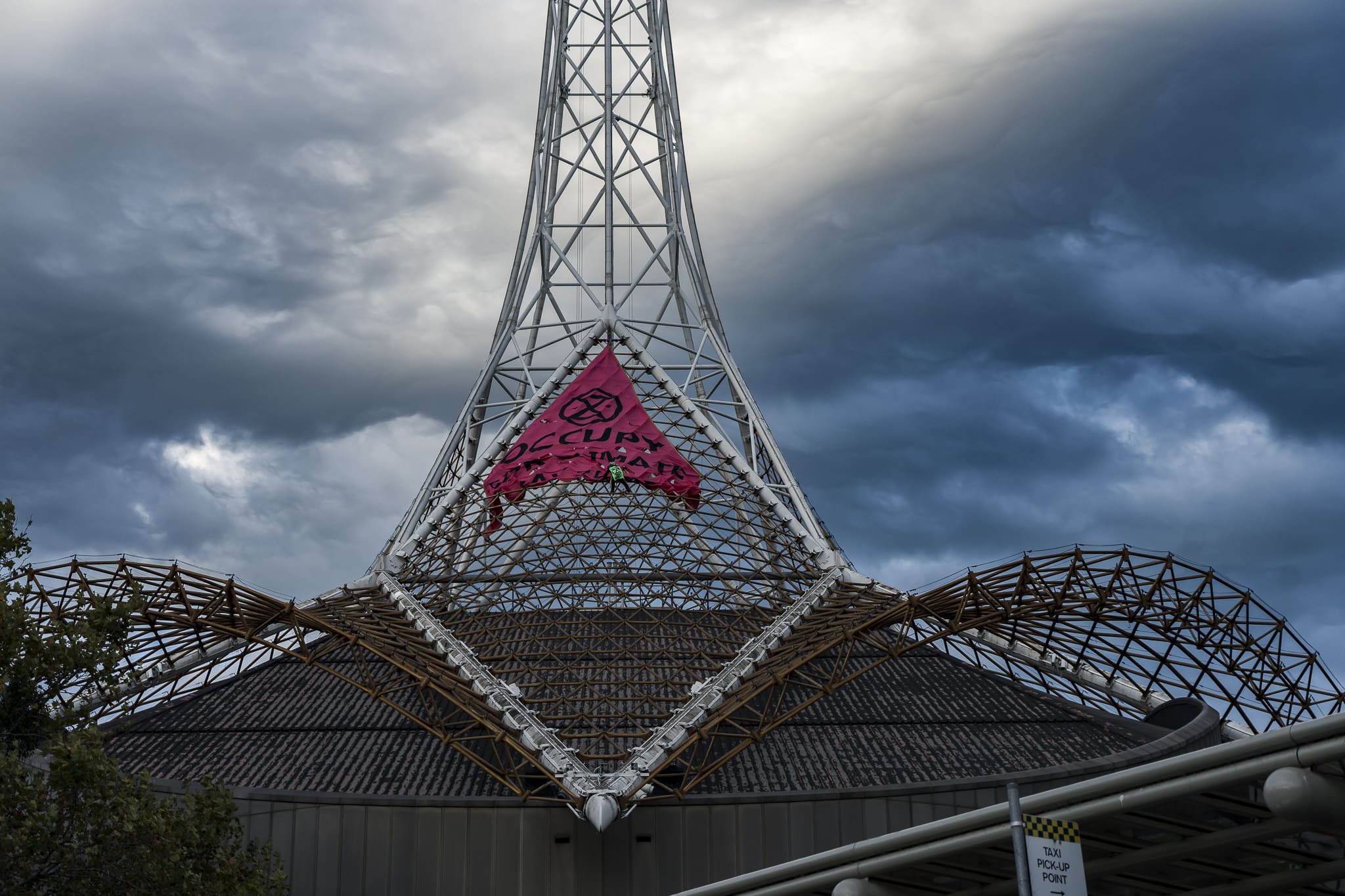 An Extinction Rebellion activist saves the Melbourne Arts Centre spire, unfurling a banner reading 'Occupy for Climate'. Photo: Matt Hrkac