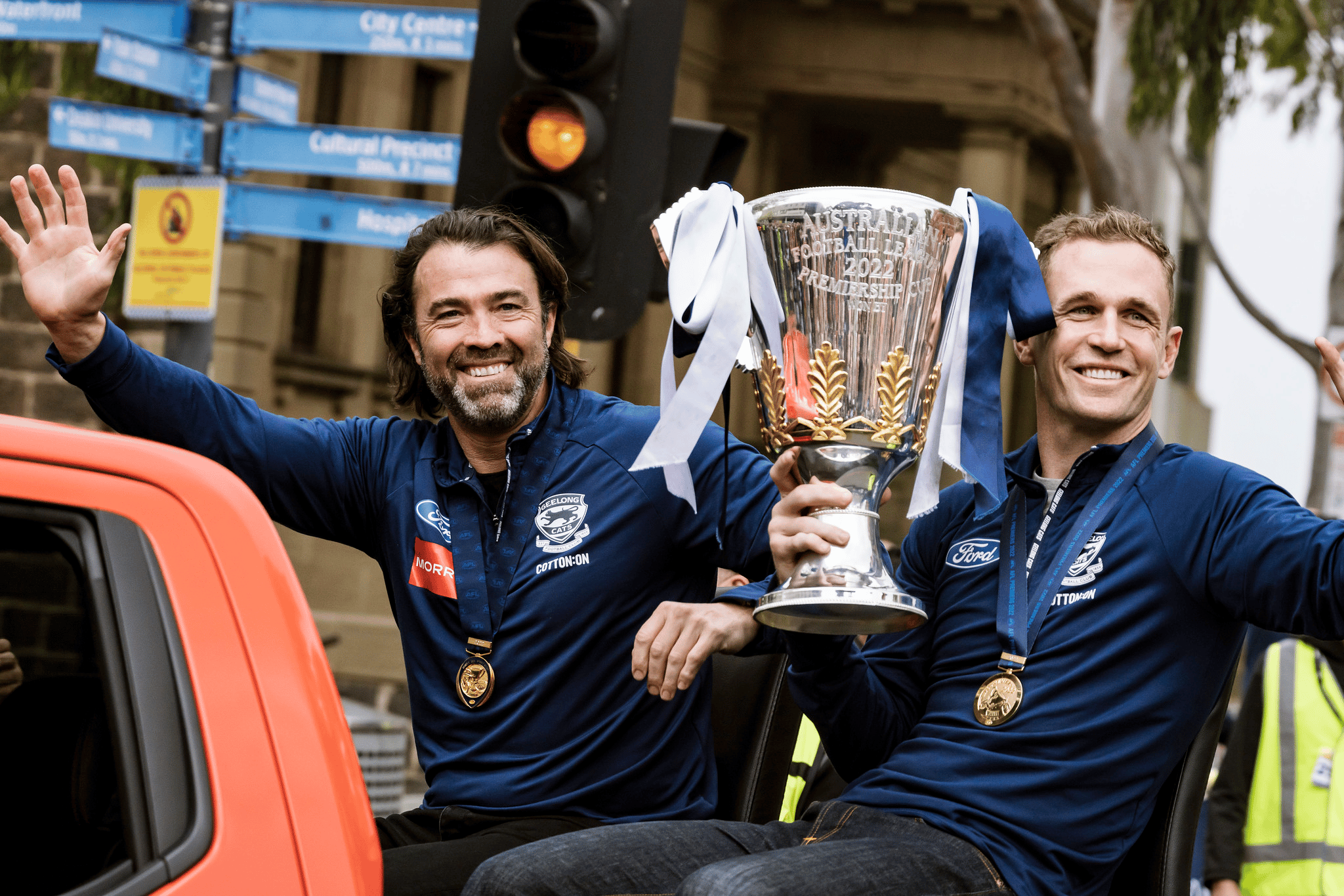 Geelong Cats coach Chris Scott sits alongside then-captain Joel Selwood who's holding the premiership cup.