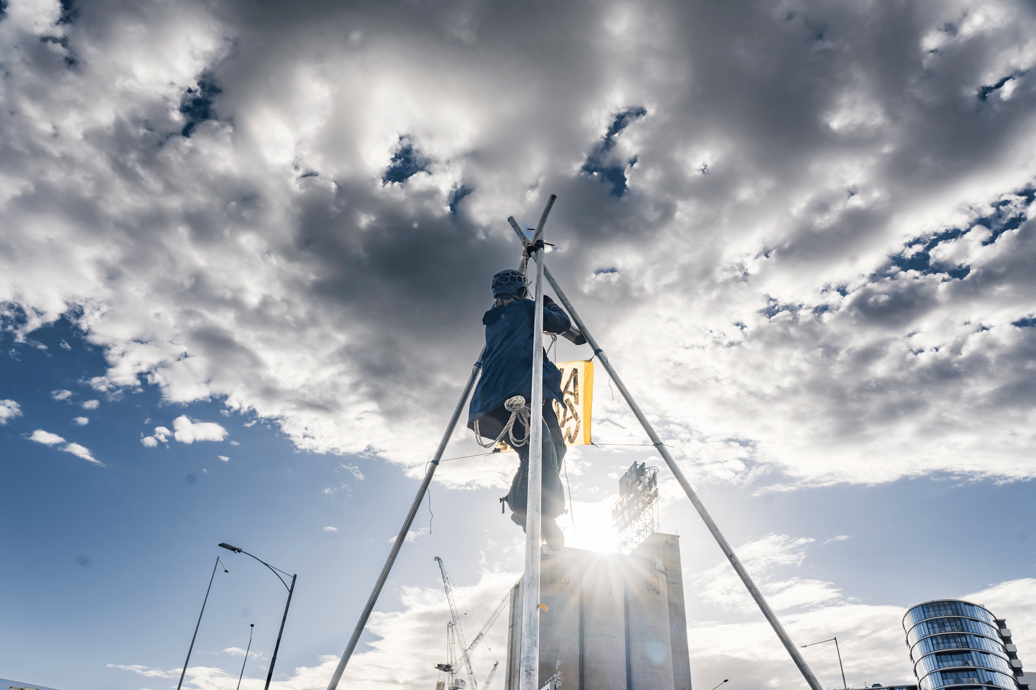 A protester suspends themselves atop a tripod on Punt Road Bridge in solidarity with Gunditjmara People opposed to seismic blasting